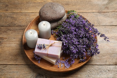 Photo of Burning candles, stones, soap bars and lavender flowers on wooden table