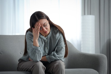 Photo of Stressed young woman on sofa at home