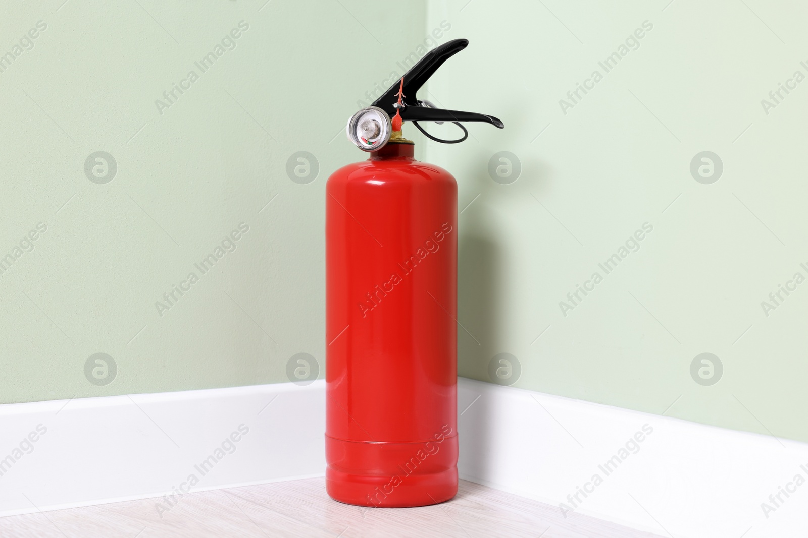 Photo of Red fire extinguisher near light green wall