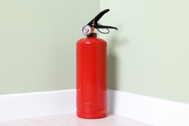 Red fire extinguisher near light green wall