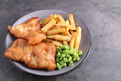 Photo of Tasty fish, chips and peas on grey table