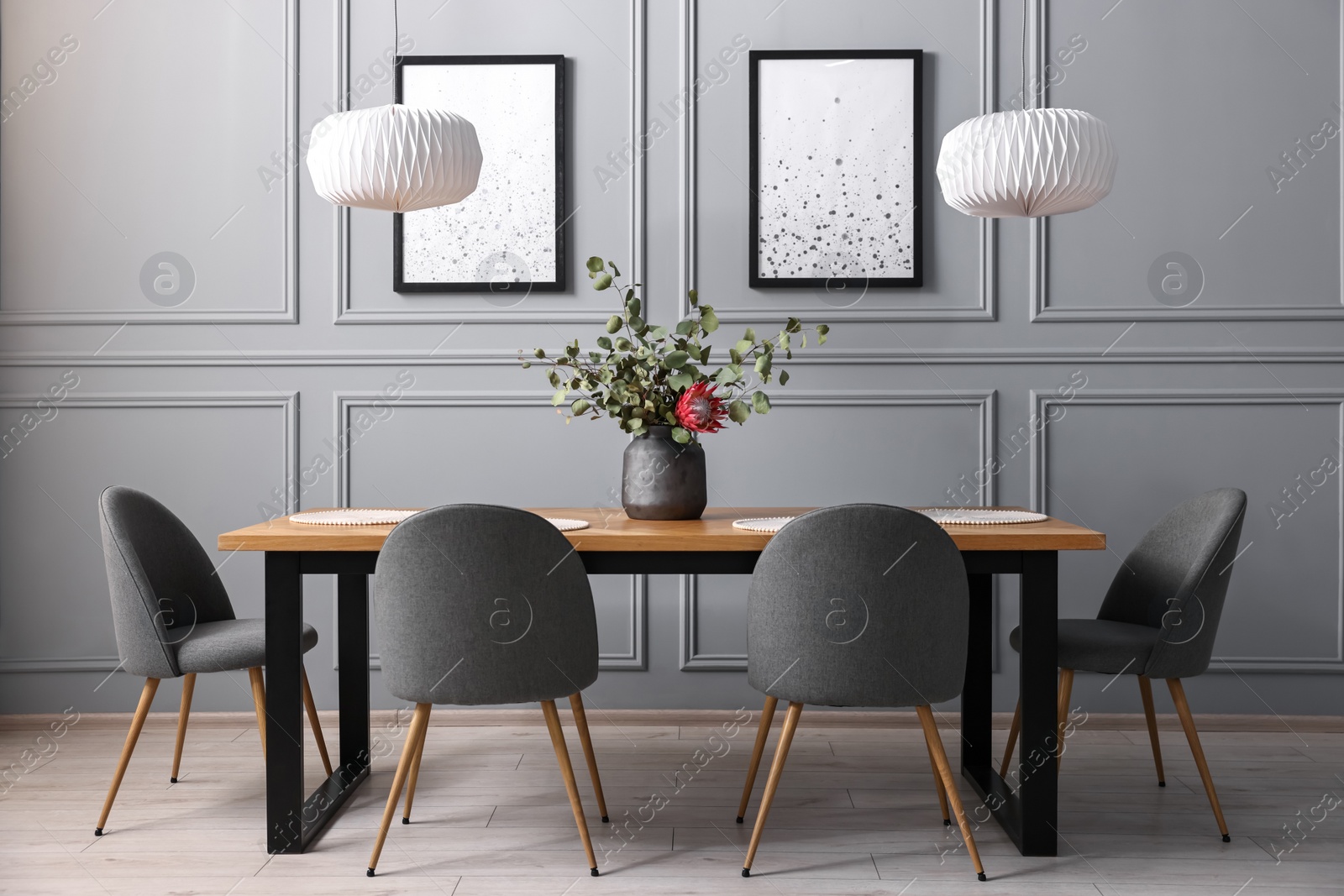 Photo of Soft chairs, table and vase with plants in stylish dining room