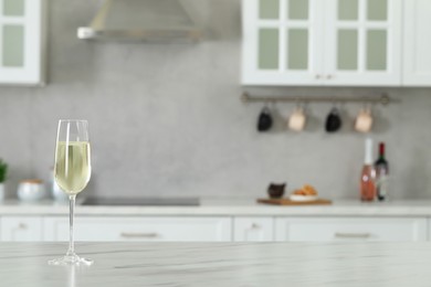 Photo of Glass of wine on white marble table in kitchen. Space for text