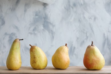 Photo of Juicy pears on wooden table against light background