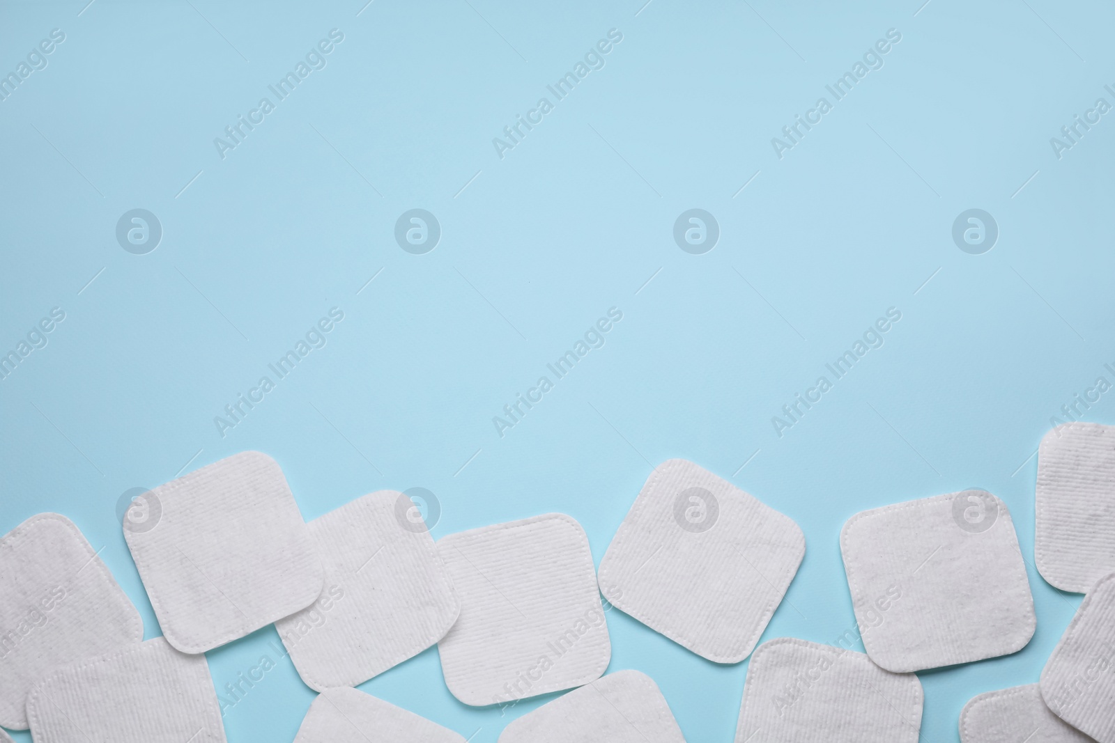 Photo of Many cotton pads on light blue background, flat lay. Space for text