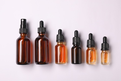 Bottles of essential oils on light background, top view. Cosmetic products