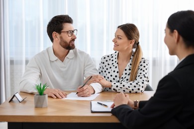 Happy couple signing document in lawyer's office