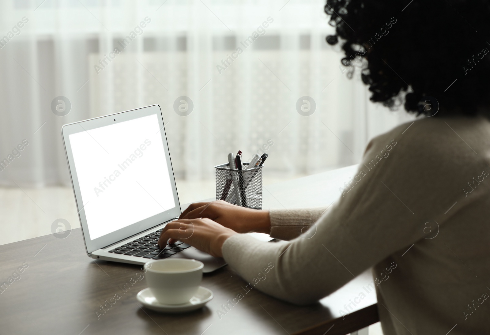 Photo of Woman using laptop at wooden desk indoors, closeup