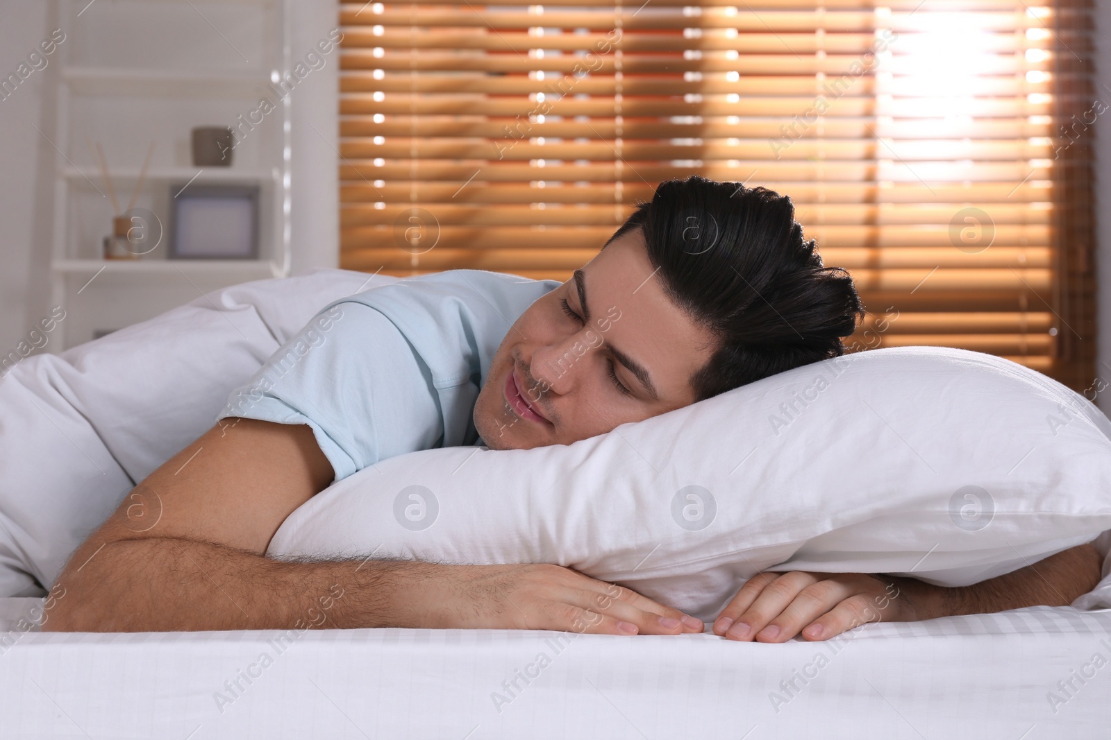 Photo of Man sleeping in comfortable bed with white linens