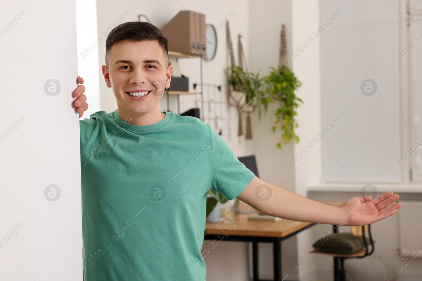 Photo of Handsome man inviting to come in room at home