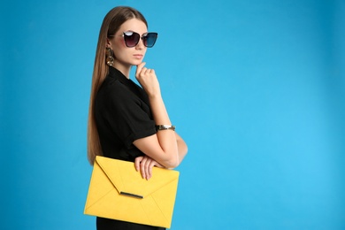 Photo of Young woman with stylish yellow bag on light blue background. Space for text