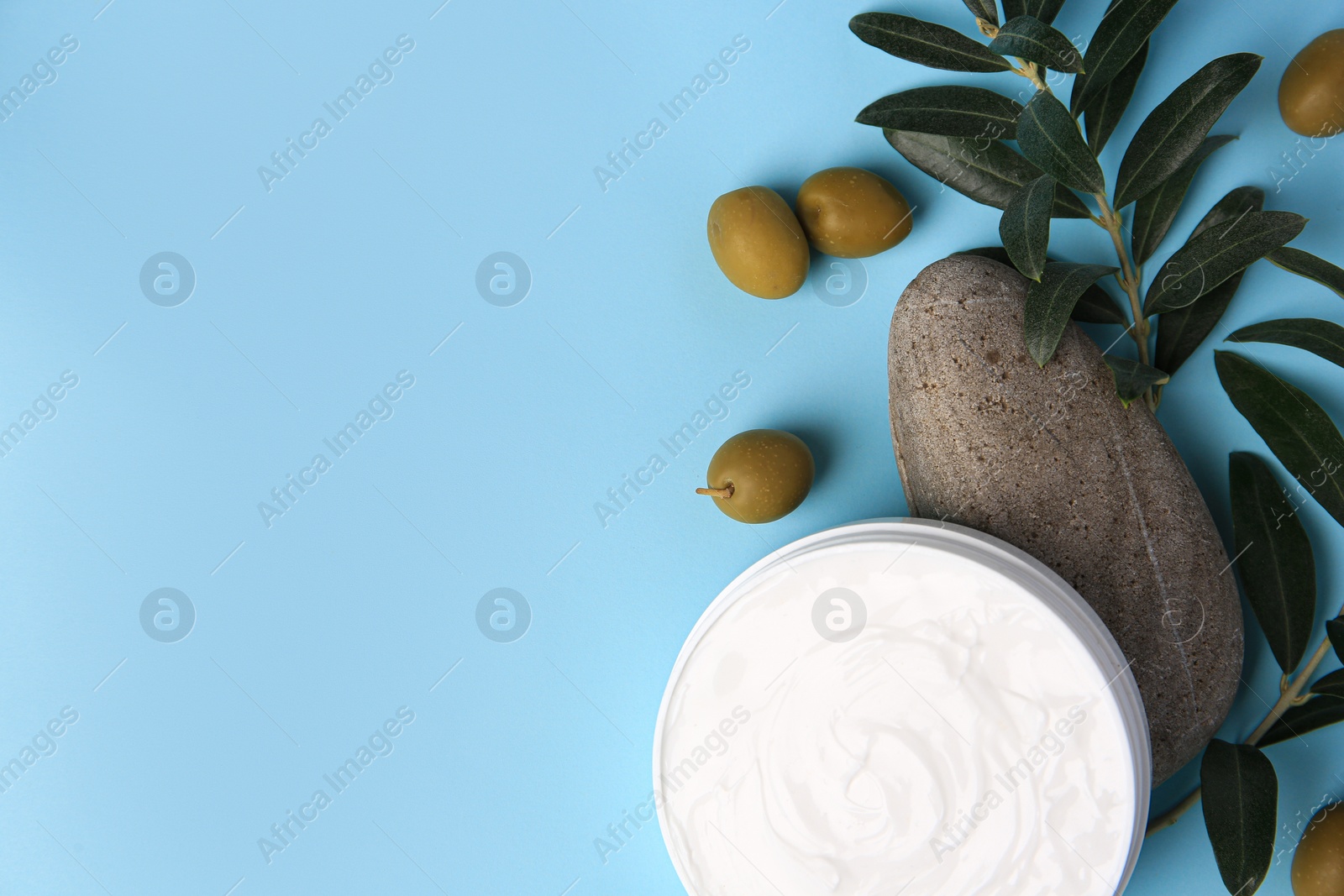 Photo of Flat lay composition with jar of cream and olives on light blue background. Space for text