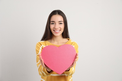 Photo of Portrait of beautiful young woman with decorative heart on light background