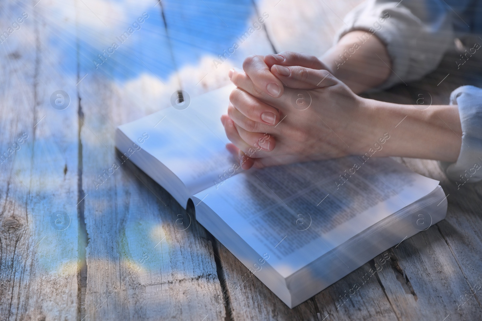Image of Religion. Double exposure of sky and Christian woman praying over Bible at table, closeup