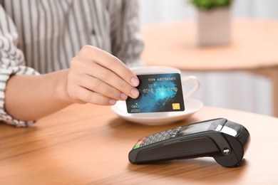 Woman using terminal for credit card payment in cafe