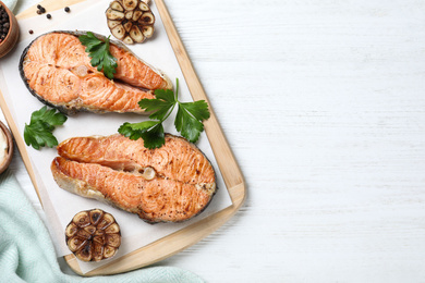 Photo of Tasty cooked red fish on white wooden table, flat lay. Space for text