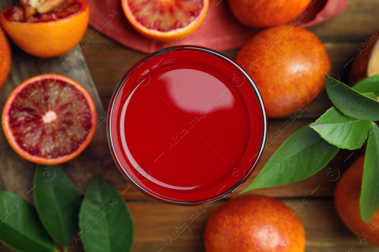 Photo of Tasty sicilian orange juice in glass and fruits on wooden table, flat lay