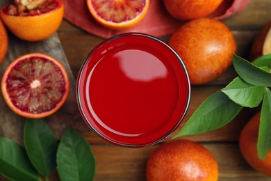 Photo of Tasty sicilian orange juice in glass and fruits on wooden table, flat lay