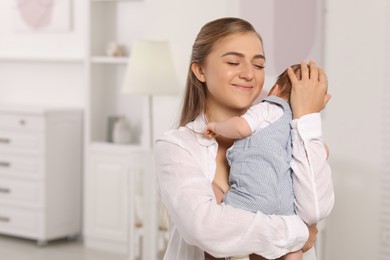 Photo of Mother holding her cute newborn baby in child's room, space for text