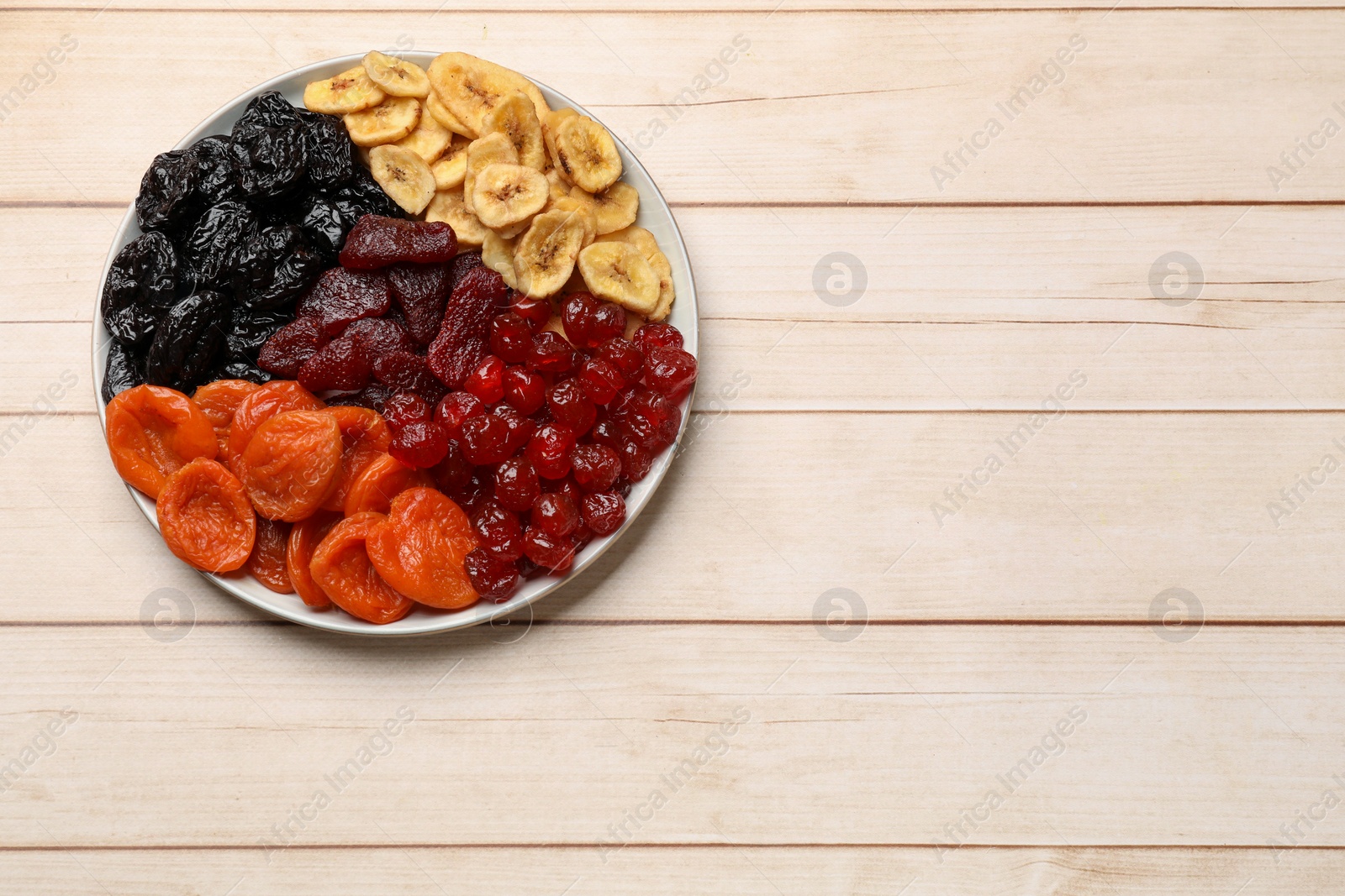 Photo of Delicious dried fruits on white wooden table, top view. Space for text