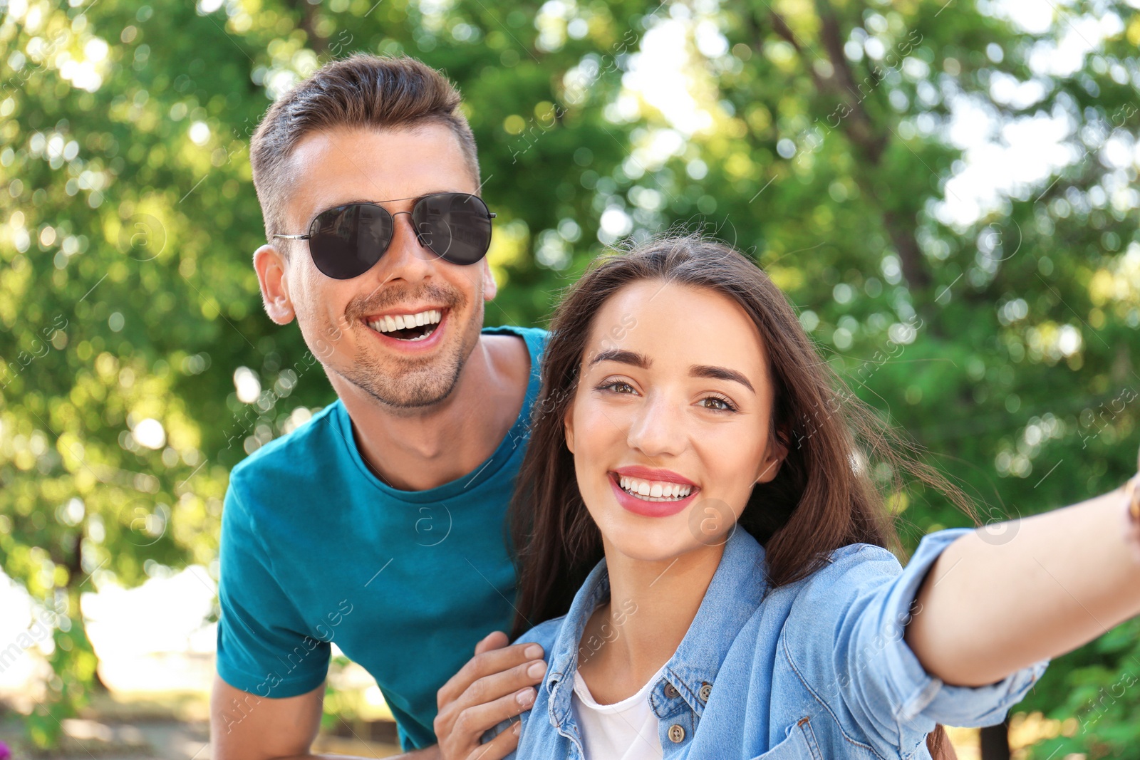 Photo of Young couple taking selfie outdoors on sunny day