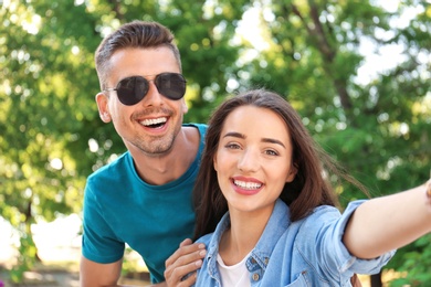 Photo of Young couple taking selfie outdoors on sunny day