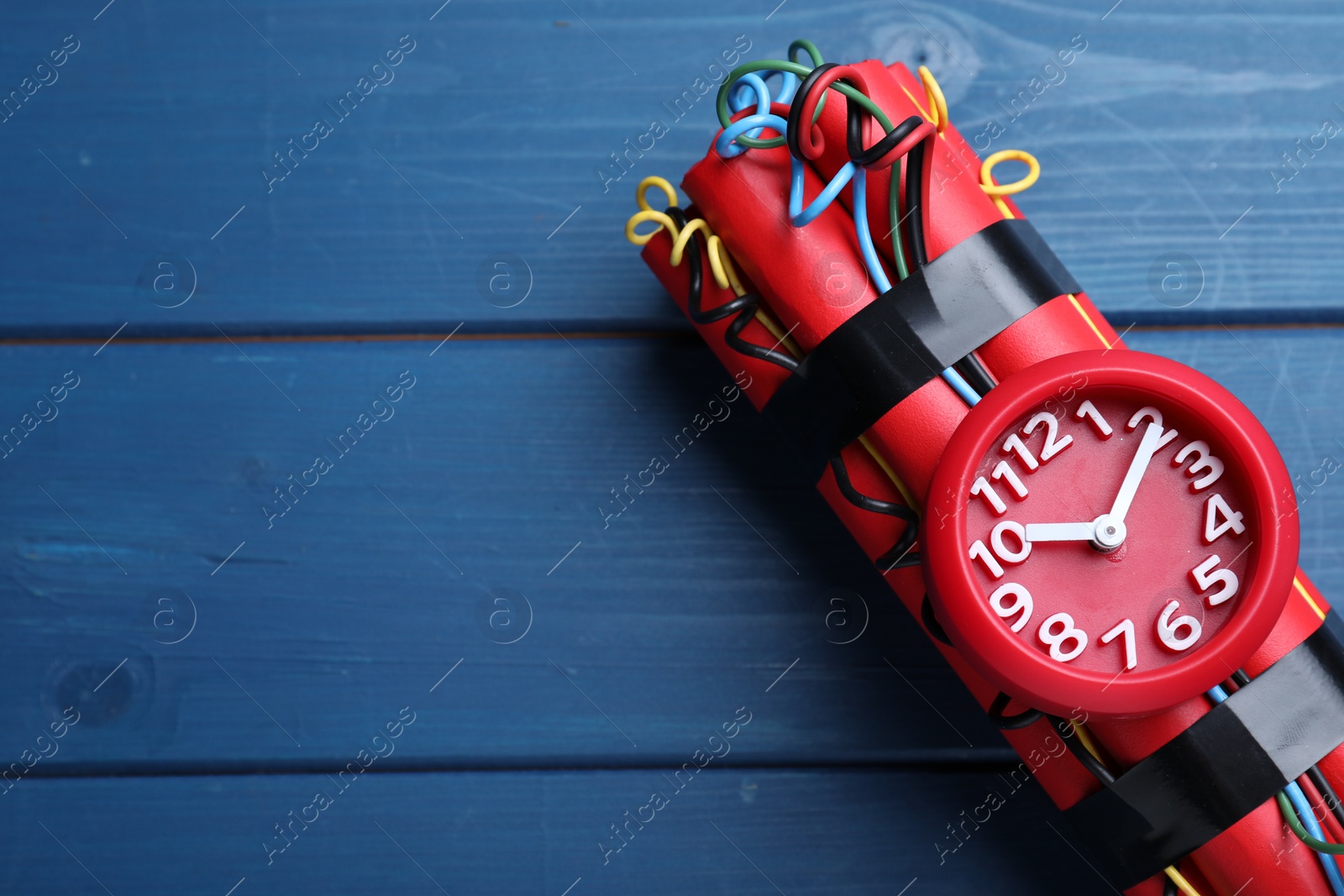 Photo of Dynamite time bomb on blue wooden table, top view. Space for text