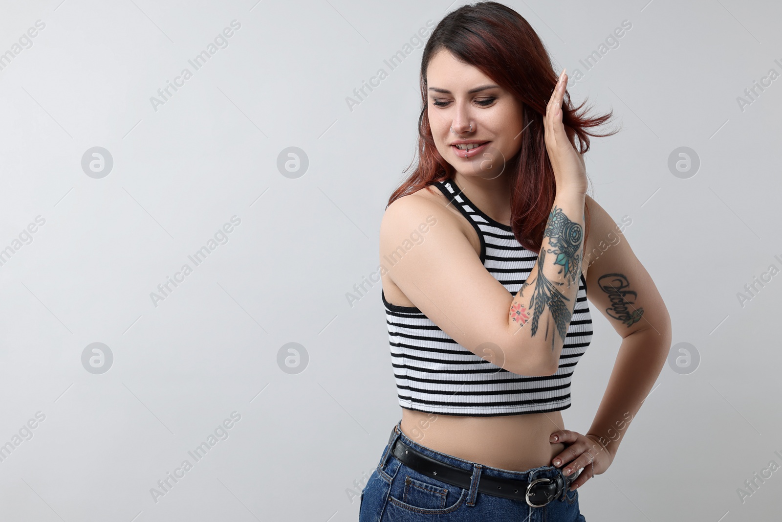 Photo of Beautiful tattooed woman on gray background, space for text