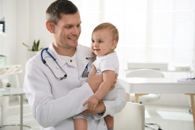 Pediatrician with cute little baby in clinic. Space for text