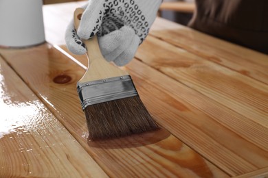 Man varnishing wooden surface with brush, closeup