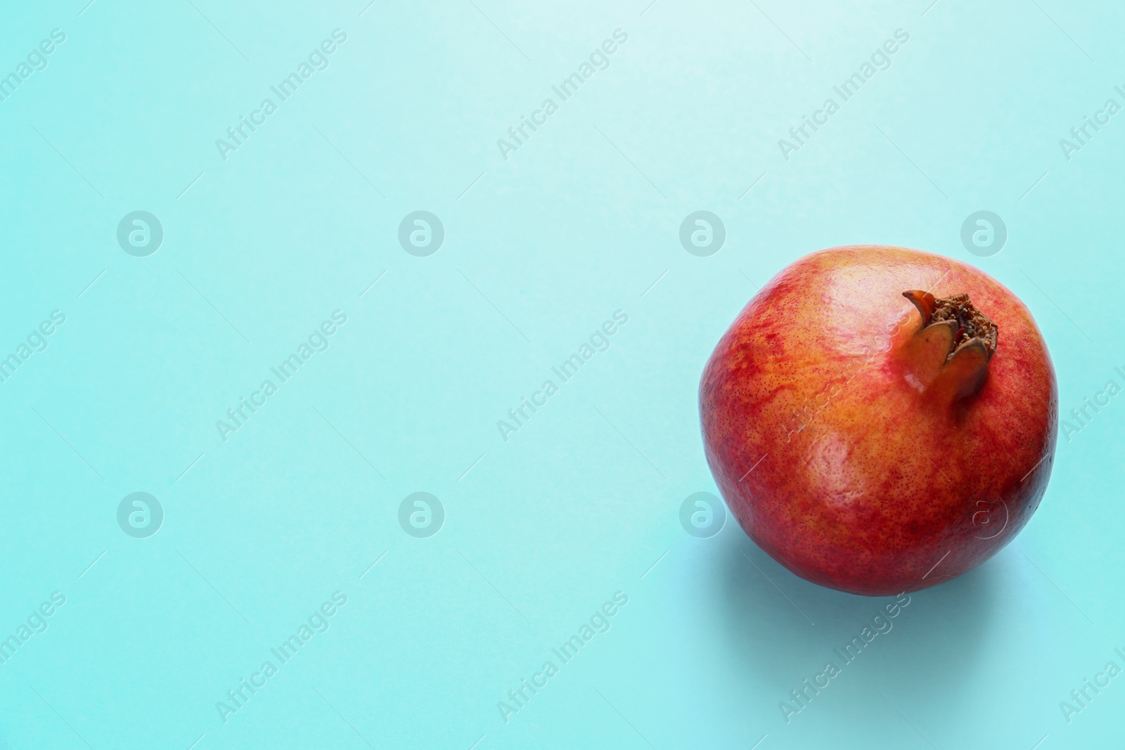 Photo of Tasty raw pomegranate on blue background, space for text