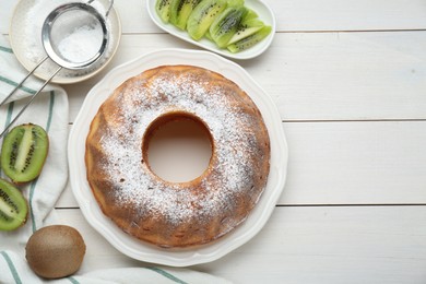 Photo of Homemade yogurt cake with kiwi and powdered sugar on white wooden table, flat lay. Space for text