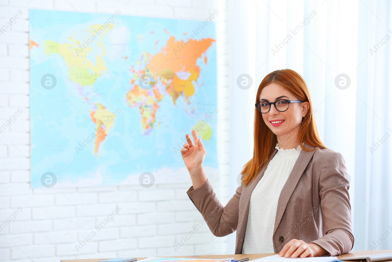 Photo of Beautiful consultant showing map in travel agency. Space for text