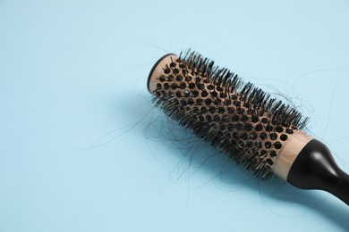 Photo of Professional brush with lost hair on light blue background, closeup. Space for text