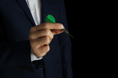 Photo of Man holding green dart on black background, closeup