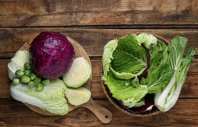 Different types of cabbage on wooden table, flat lay