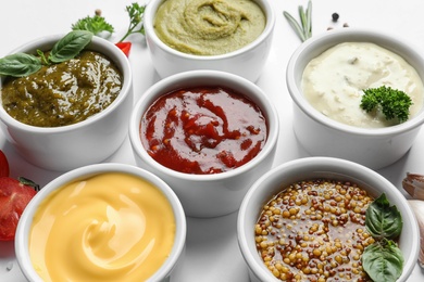 Photo of Bowls with different sauces on white background