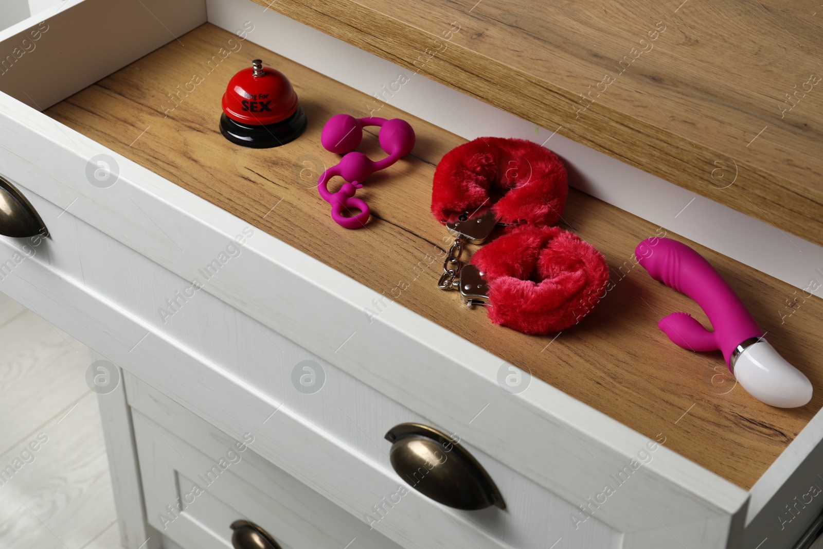 Photo of Different modern sex toys in open wooden drawer