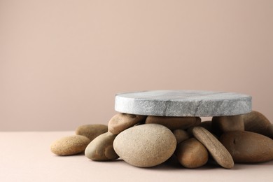 Photo of Presentation for product. Stone podium and pebbles on beige background. Space for text