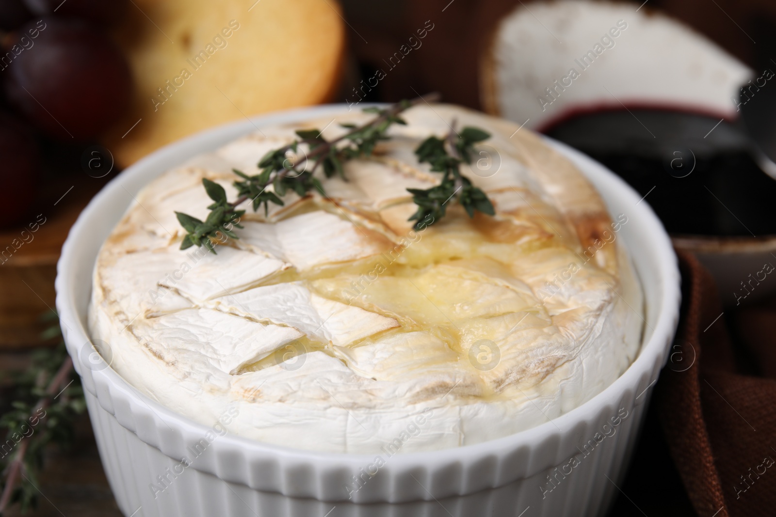 Photo of Tasty baked camembert and thyme in bowl on table, closeup