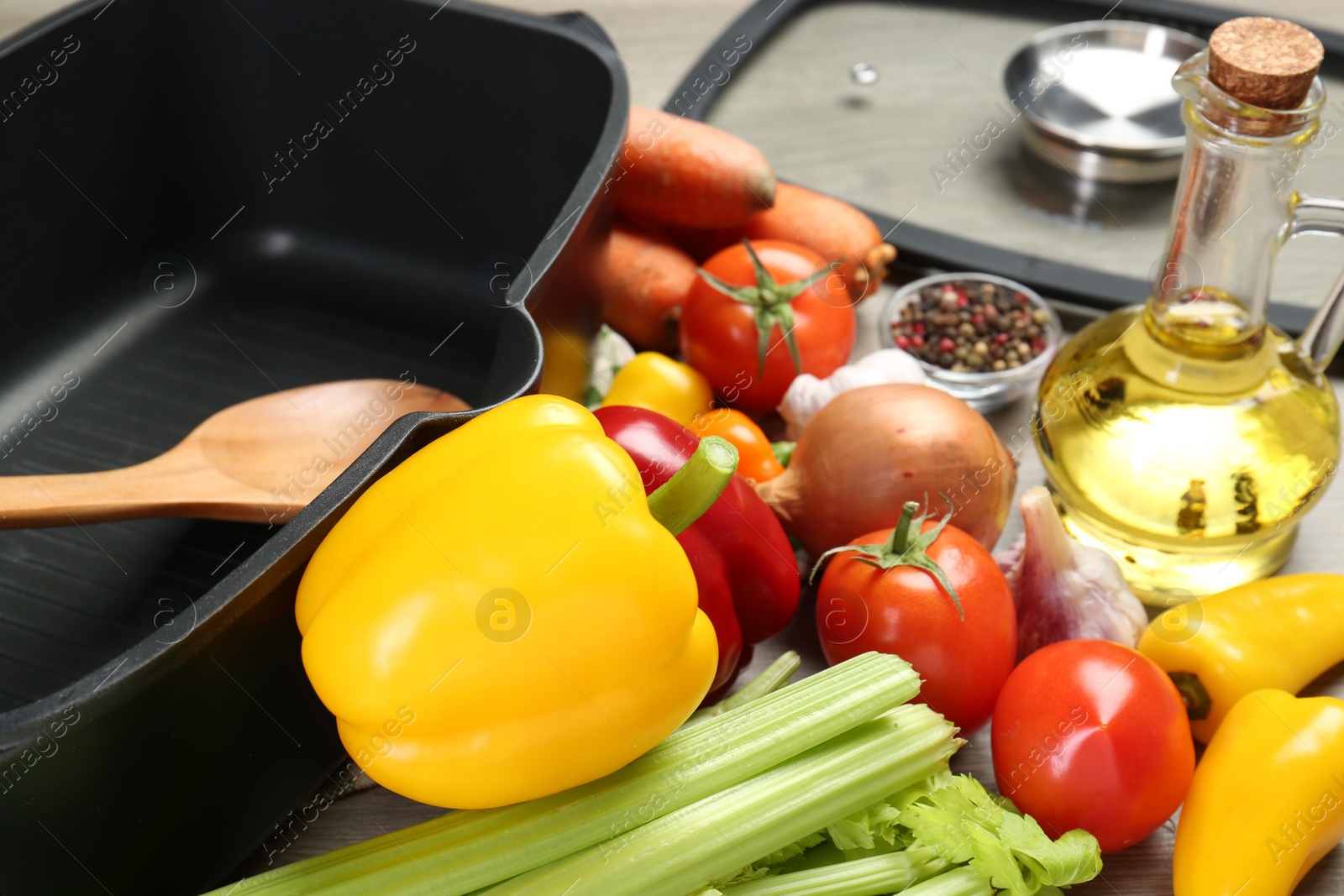 Photo of Black pot, wooden spoon and fresh products on table