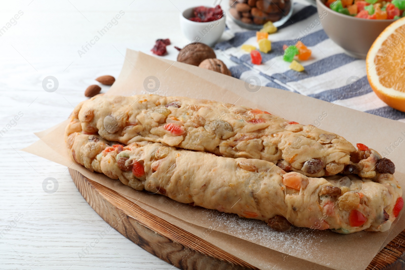 Photo of Unbaked Stollen with candied fruits and raisins on white wooden table, closeup