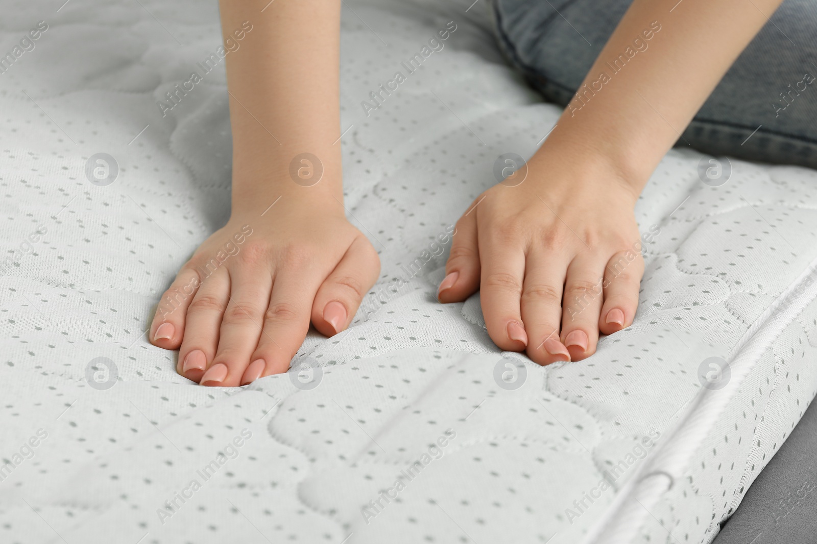 Photo of Woman touching new soft mattress, closeup view