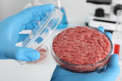 Scientist holding Petri dish with raw minced cultured meat in laboratory, closeup