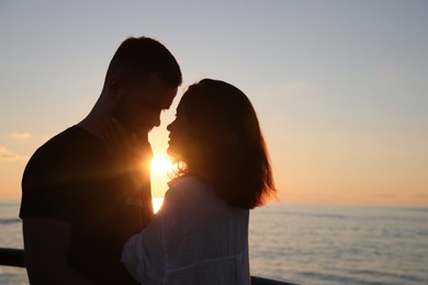 Photo of Happy young couple together near sea at sunset