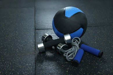 Photo of Blue medicine ball, dumbbells and skipping rope on floor, space for text