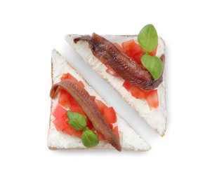 Delicious sandwiches with cream cheese, anchovies, tomatoes and basil on white background, top view