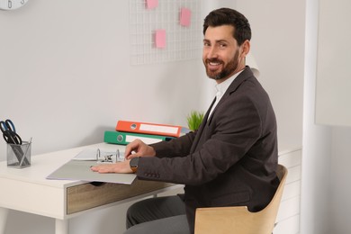 Photo of Businessman with file folder at white table in office