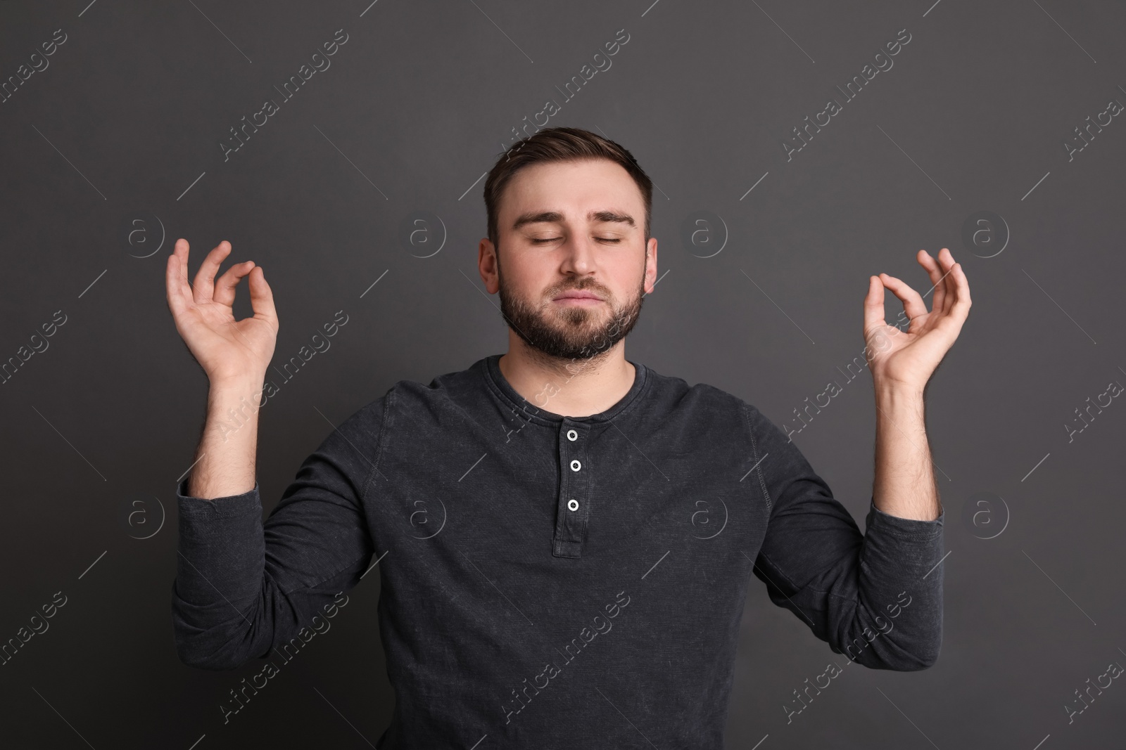 Photo of Young man meditating on grey background. Personality concept