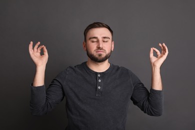 Photo of Young man meditating on grey background. Personality concept